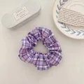 Gros plan d'un chouchou en tissu à carreaux violets sur un fond de table esthétique - Carreaux Violet Raisin