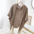 Detailansicht eines beigen Strick-Ponchos mit Wellenmuster-Textur. - Dreiecksschal mit Lederschnalle (Oberteil) / Khaki