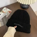 Unisex black winter knitted beanie hat with unique and casual label detail view - One Size / Long Tag Style / Black