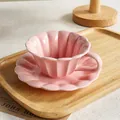Elegant pink scalloped ceramic coffee cup and saucer set displayed on wooden tray - Cup And Saucer / Pink