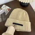 Cozy beige ribbed knit beanie featuring a black text label for stylish winter warmth - One Size / Long Tag Style / Beige