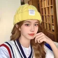 Bright yellow knitted slouchy beanie hat for winter worn by model in indoor room setting - One Size / Twisted Chain / Yellow