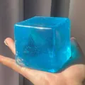 Blue translucent ice cube squishy toy for stress relief held in a person's palm - Large Ice Cube Shape / 5cm (OPP Bag) / Blue