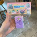 Detail view of a purple cake-shaped decompression squeeze toy in clear plastic packaging - Cake Bar / Purple
