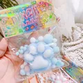 Macro detail of a soft blue cat paw squishy toy in its colorful iridescent packaging. - Blue Plush