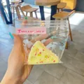 Λεπτομερής άποψη ενός κίτρινου squishy παιχνιδιού σε σχήμα κέικ σε διάφανη συσκευασία. - Τριγωνικό Τυρί / Κίτρινο