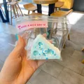 Κοντινό πλάνο ενός μπλε παιχνιδιού squishy τούρτα Βάσκων που κρατιέται στο χέρι σε σακούλα. - Τριγωνικό Τυρί / Μπλε
