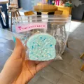 Μακροσκοπική άποψη ενός μπλε squishy παιχνιδιού τοστ σε σακουλάκι με ροζ αυτοκόλλητο - Κέικ Σάντουιτς Τοστ / Μπλε