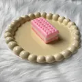 Close-up view of a pink soda cracker sandwich squishy toy on a beige decorative plate - Soda Cracker Strawberry