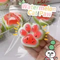 Close-up of cat paw watermelon squishy toy being squeezed in hand - Watermelon Cat Paw - White Base