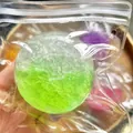 Detailed shot of a green squishy stress relief toy with shredded ice filler in a bag. - 6cm / Green