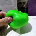 Detailed macro shot of a slushy green apple squishy toy being squeezed by hand - Slushy Green Apple