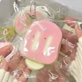 Close-up van squishy broodspeelgoed met roze glazuur in plastic verpakking - PVC-zak en food-grade siliconen / Kersenbloesem roze ijsje