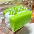 Nahaufnahme von grünem Toast-Squishy-Spielzeug mit Sahnehaube in transparenter Plastikfolie - Grüner Apfel-Sandwich