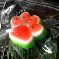 Macro view of watermelon-colored cat paw squishy stress relief toy in clear packaging - Watermelon Cat Paw