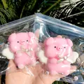 Close-up view of two pink angel pig squishy toys in clear plastic bags with decorative pearls - Angel Pig