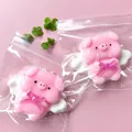 Detail showing cartoon pink flying pig squishy toy with white angel wings in a plastic bag - Angel Pig