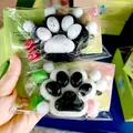 Cute cat paw squishy toy with pearl glitter finish and colorful decorative pom-poms. - Black & White Paw Print / Black and White