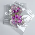 Close-up of transparent aurora cat paw squishy toy with purple strawberry glitters inside. - Eggplant Style (With Glitter) / 60g Pack / Transparent Glitter Purple