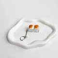 Detail view of a caramel bread-shaped fidget switch tester keychain on a ceramic tray - Double Button Style