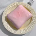 Close-up of pink strawberry toast squishy toy with red sprinkles on a white plate. - Berry Toasts
