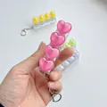Close-up of a pink heart-shaped mechanical switch tester keychain fidget toy being held - No Light / Rose Red Chubby Heart