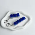 Close-up of galaxy starry blue keycap keychain fidget toys on a white tray - 3-Key Style / No Light / Dark Blue