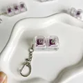 Detail view of a clear 2-key mechanical switch tester keychain on a white dish - Two-Key Style