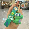 Détail d'un porte-clés dinosaure vert en PVC mignon avec sangle imprimée 'RUN FAST'. - Dinausore mignon / Vert