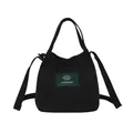 Minimalist black canvas bucket bag featuring a green letter patch and adjustable strap - Black