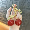 Close-up of elegant glittery red cherry keychain with gold hardware held by a hand - 3cm / Transparent Red Gold Rod P