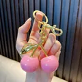 Close-up of a hand holding an elegant pink cherry keychain with polished gold hardware - 3cm / Solid Pink Gold Rod