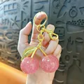 Detail view of a pink glitter cherry keychain held in hand as an elegant bag charm accessory - 3cm / Transparent Pink Gold Rod