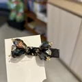 Close-up detail of an elegant black rhinestone bow hair clip featuring luxury gold metal accents - Black-Grey Side Hair Clip