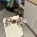 Macro detail of a luxurious pink rhinestone bow hair clip on a white display card - Purple Side Hair Clip