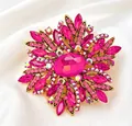 Detail shot of a large sunburst brooch with hot pink crystals on white silk background. - Rose Red