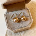 Elegant golden hook earrings featuring large round champagne pearls in a velvet jewelry box - Champagne Pearl (1864) / 12mm / Gold
