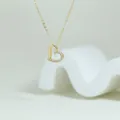 Close-up of a gold heart pendant necklace with pave crystal details on white prop - Gold and Silver Bicolor Style (1)