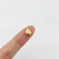 Makroansicht eines kleinen goldenen Pinguin-Anhängers aus Edelstahl auf einer Fingerspitze - 1# (Pinguin)