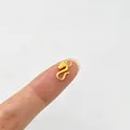 Detaillierte Makroaufnahme eines goldenen Drachen-S-Hakens auf einer Fingerspitze für DIY-Schmuck - Seepferdchen / Seepferdchen-Stil (Gold)