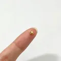 Macro view of a tiny golden faceted stainless steel spacer bead on a fingertip for scale - Large Polygon Style (6284455362259)
