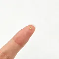 Macro view of a tiny gold faceted stainless steel spacer bead on a fingertip - Small Polygon Style (6284455362260)
