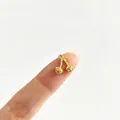 Nahaufnahme eines winzigen goldenen Kirschherz-Anhängers auf einem Finger als Maßstab. - Herzförmige Frucht Kirschstil (3#)