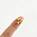 Detailaufnahme eines winzigen goldenen Kirsch-Anhängers auf einer Fingerspitze zur Größenangabe - Realistischer 3D-Kirschstil (4#)
