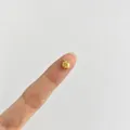 Detailansicht eines 18K Gold Apfel-Anhängers auf einer Fingerspitze zum Größenvergleich. - Apfelform (3#) / Gold