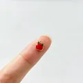 Kleiner roter Emaille-Apfelanhänger auf der Fingerspitze zeigt die Miniaturgröße - Apfel-Stil (4#) / Dunkelrot