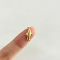 Pequeño colgante de tiburón minimalista de acero inoxidable dorado mostrado en la punta del dedo. - Tiburón (P4-5)