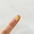 Vista macro de un colgante de hoja dorada en la punta de un dedo para joyas de bricolaje - Hoja (P4-5)