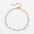 Bracelet de cheville doré en acier avec des breloques œil bleu en émail en détail. - 23+5cm / Chevillère dorée - œil blanc
