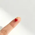 Detaillierte Nahaufnahme eines winzigen roten Erdbeer-Anhängers auf einer Fingerspitze für die Größe - Erdbeerstil (3#)